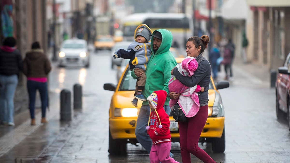 Ciudadanos abrigados cruzan las calles ante el repentino descenso de temperaturas en el noroeste de México.