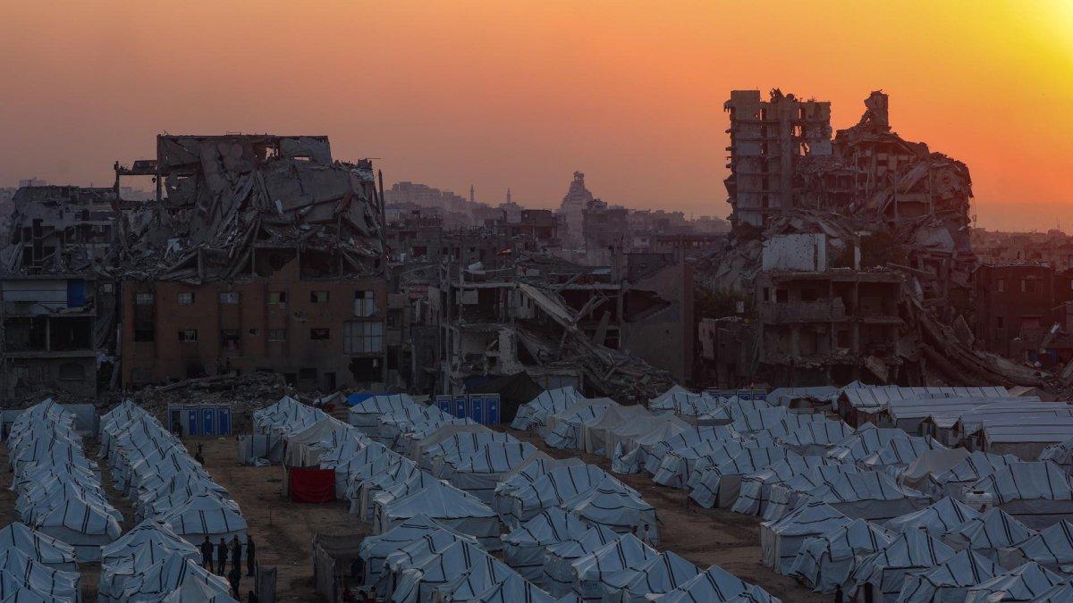 El sol se pone tras las ruinas de edificios destruidos y filas de tiendas de campaña de familias desplazadas en la Franja de Gaza, el 18 de noviembre de 2025.