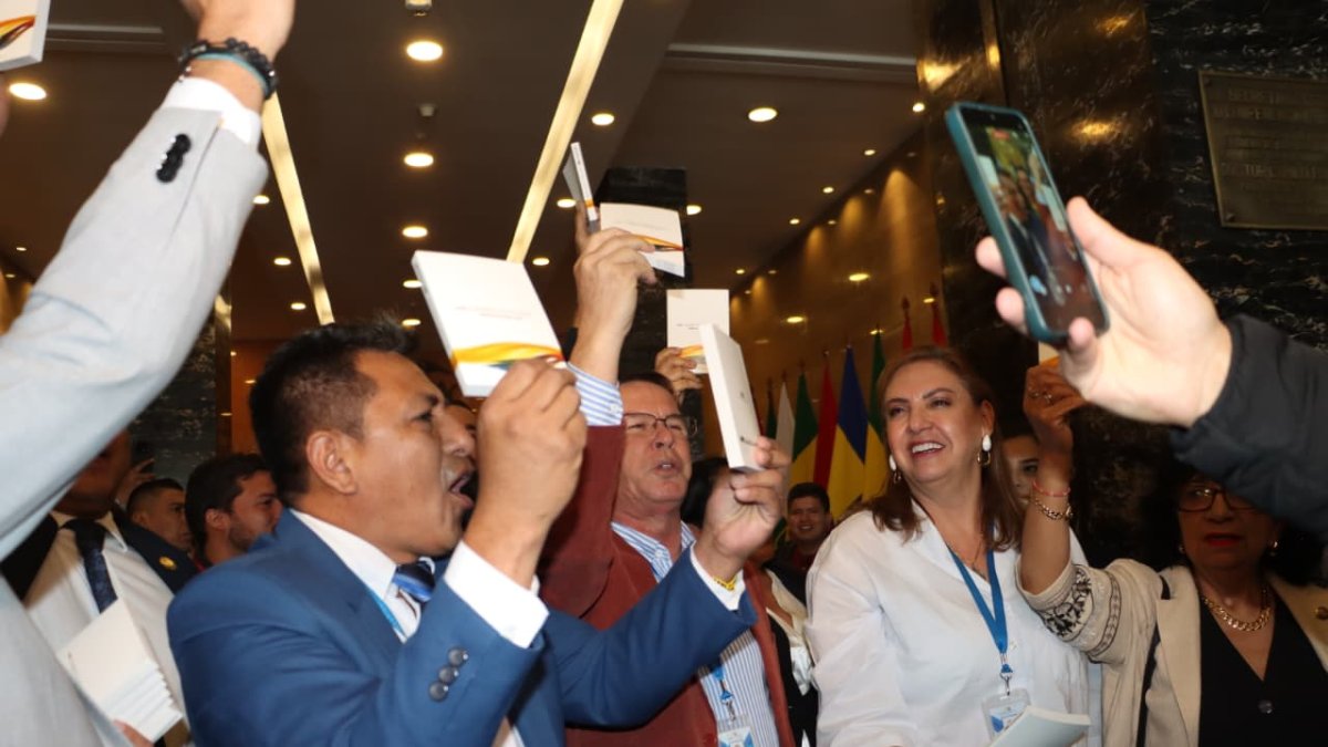 Asambleístas y militantes de Revolución Ciudadana levantan ejemplares de la Constitución de Montecristi en el hall de la Asamblea Nacional, celebrando el triunfo del “No” en la consulta popular. 