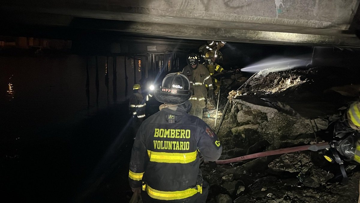 Bomberos realizan tareas de limpieza tras el incendio en la parte baja del Puente de la A, en el suroeste de Guayaquil.