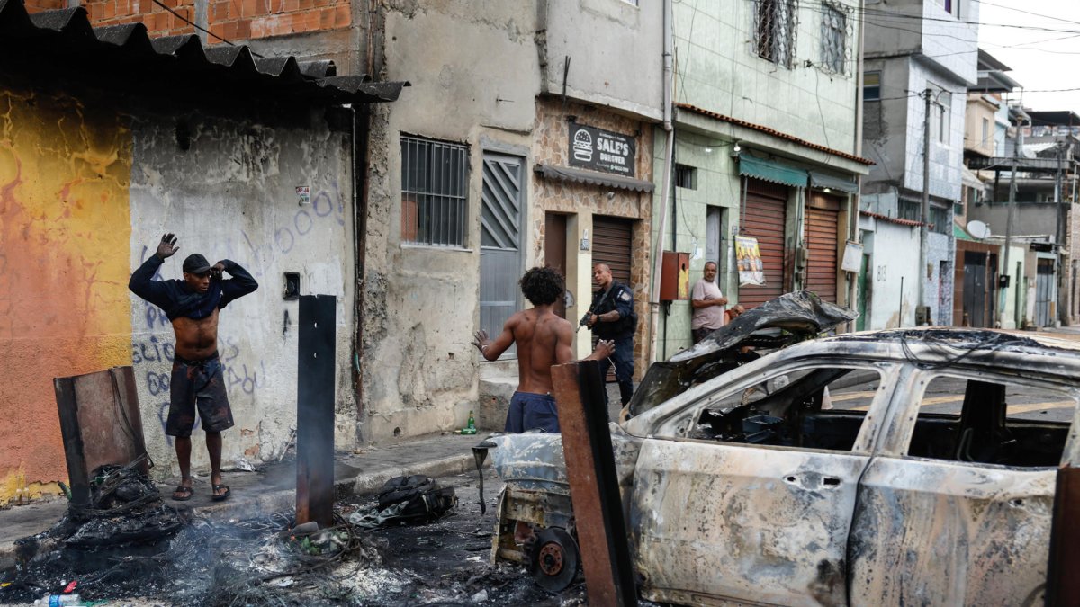 Un integrante de la Policía de Río de Janeiro custodia a dos personas durante un operativo, en Río de Janeiro (Brasil).