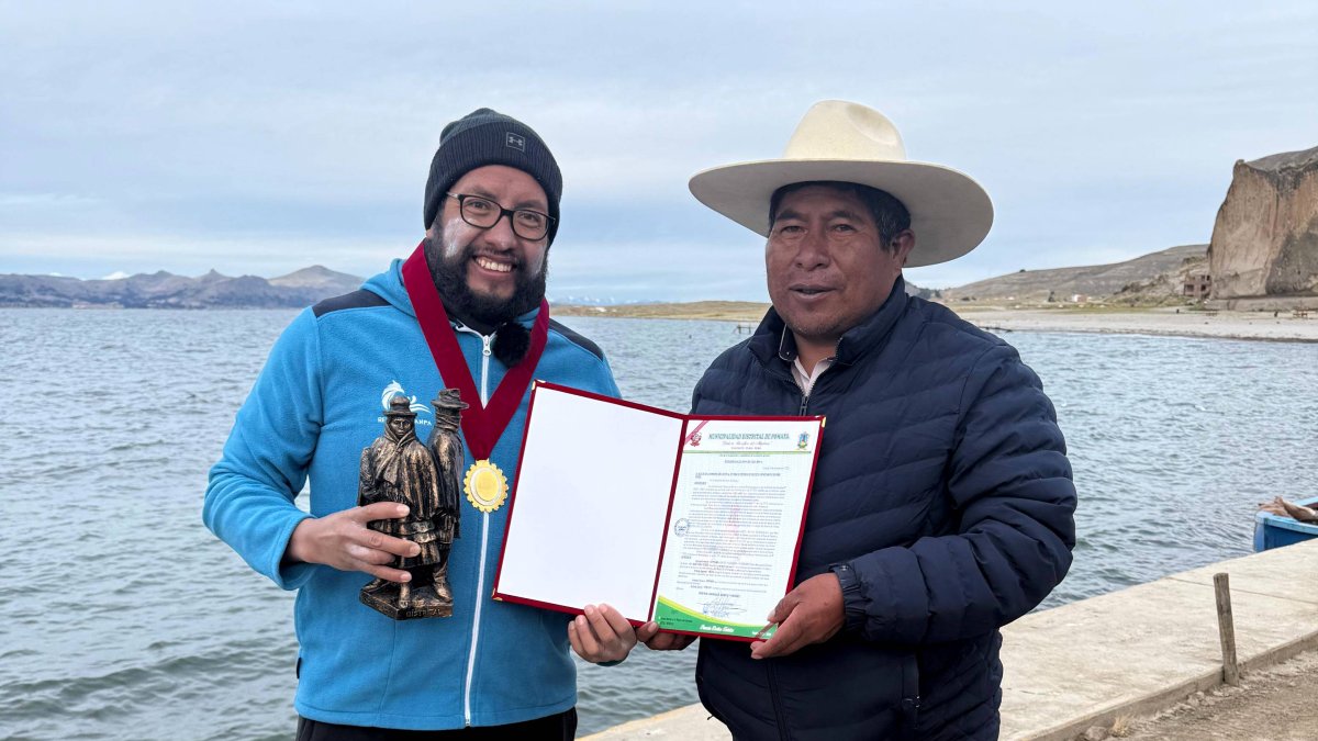 El ultranadador ecuatoriano Juan Pablo Flores (i) recibió un certificado por haber completado los 21 kilómetros entre la ruta Gruta de Lourdes (Bolivia) - Pomata (Perú).