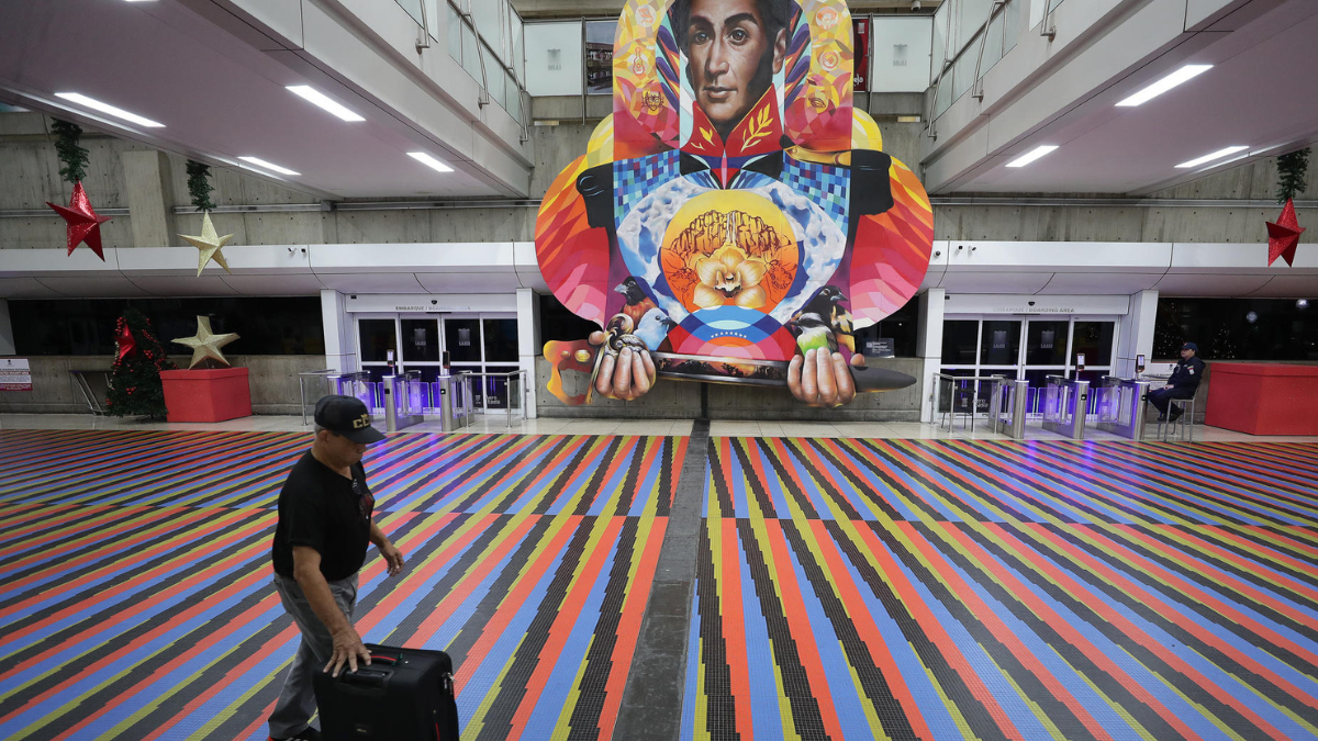 Pasajero camina frente a una imagen de Simón Bolívar en el aeropuerto de Maiquetía durante el plazo otorgado a las aerolíneas para retomar operaciones.