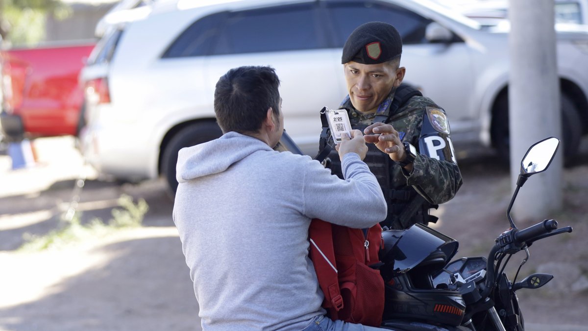Un integrante de la Policía Militar de Honduras revisa el documento de un ciudadano en Tegucigalpa.