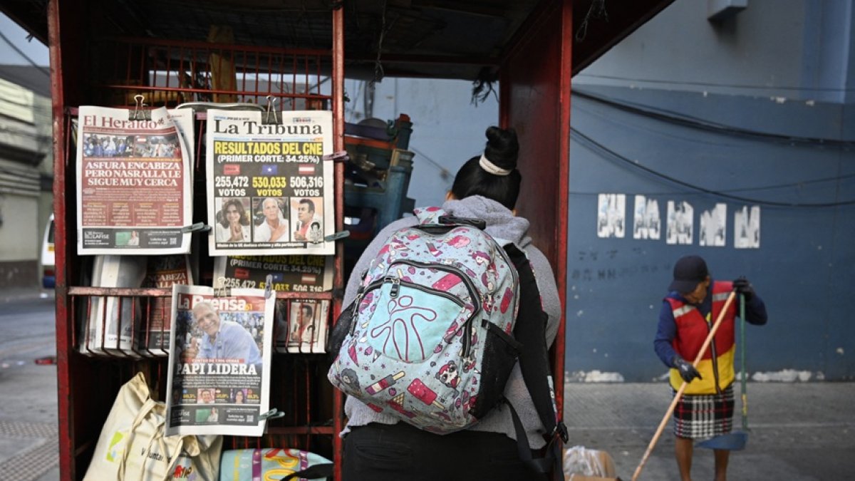 Una mujer se encuentra frente a un quiosco que muestra las portadas de los periódicos en Tegucigalpa, el 1 de diciembre de 2025, el día después de las elecciones nacionales.
