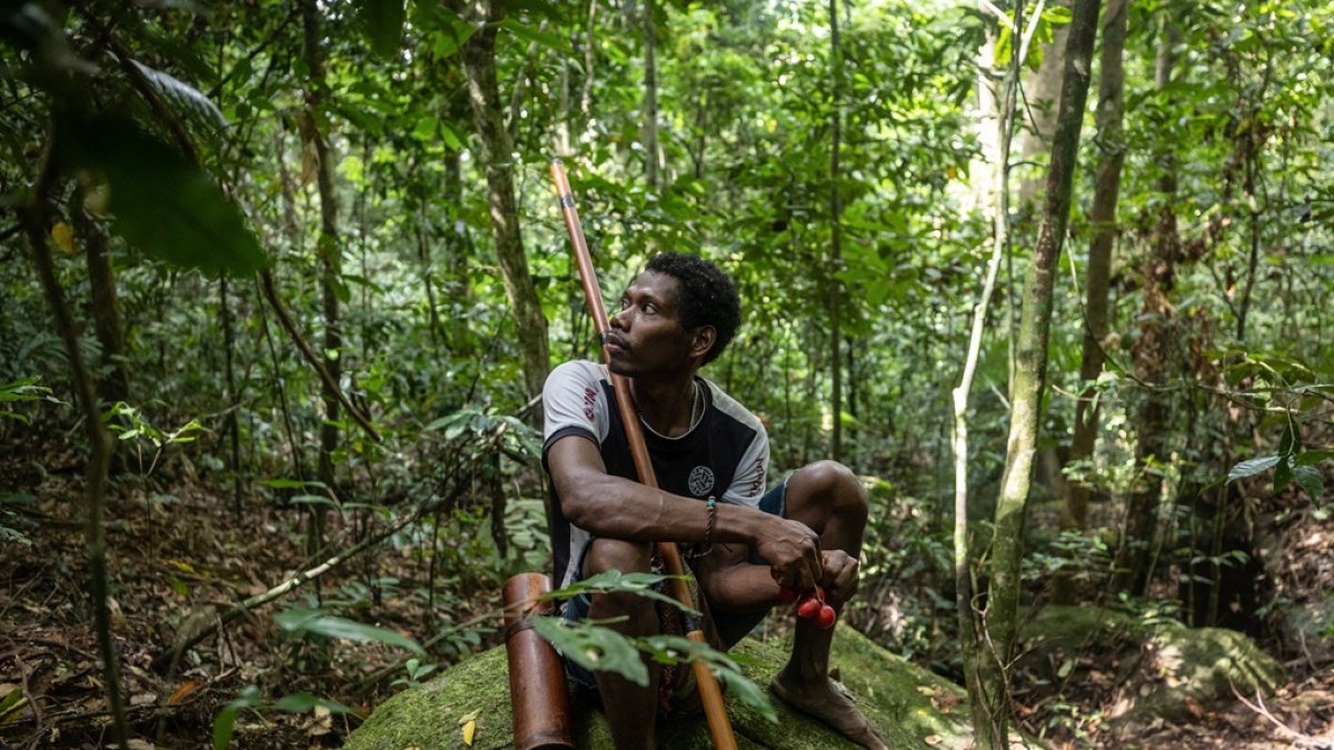 Un hombre maniq descansando en una roca y comiendo fruta silvestre, durante una expedición de caza en Phatthalung, en el sur de Tailandia.