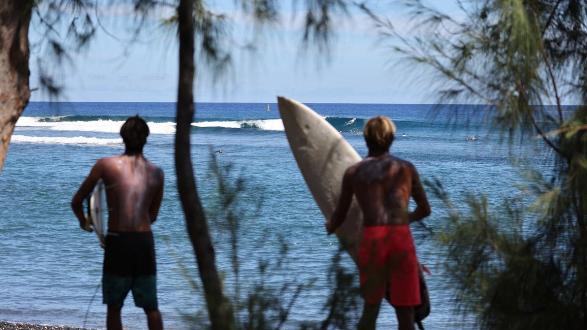 Los surfistas practican en el spot de surf de Saint-Leu, en la isla francesa de La Reunión, en el océano Índico, el 26 de marzo de 2021.