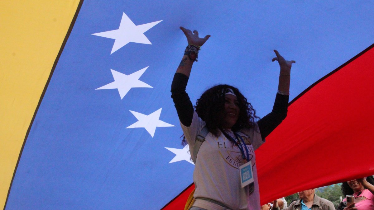 Una mujer camina debajo de una bandera durante la marcha