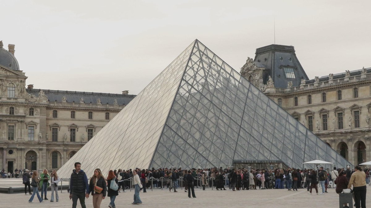 Vista del museo del Louvre de París en Francia, que aparece rodeado de turistas.
