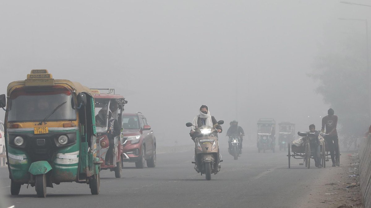 Vehículos transitan por calles en Nueva Delhi con poca visibilidad debido a la contaminación del aire en India.