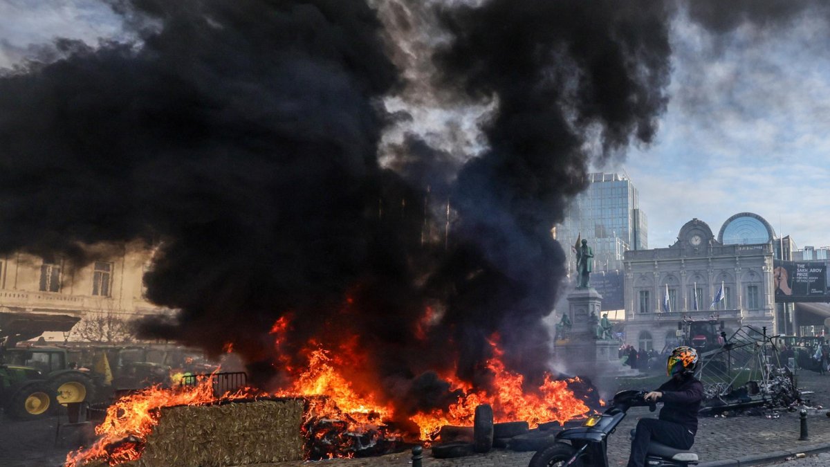 Un motociclista hace un wheelie pasando por un montón de neumáticos en llamas durante una protesta de agricultores en Bruselas, Bélgica, 18 de diciembre de 2025.