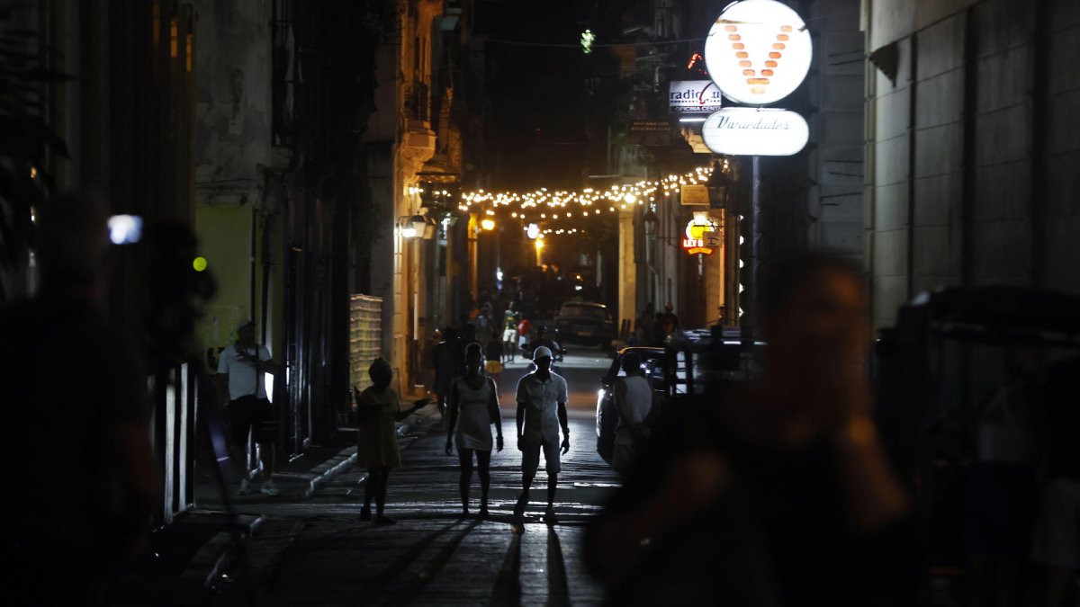 Personas caminan por una calle adornada con luces de navidad este domingo, 21 de diciembre de 2025, en La Habana (Cuba).