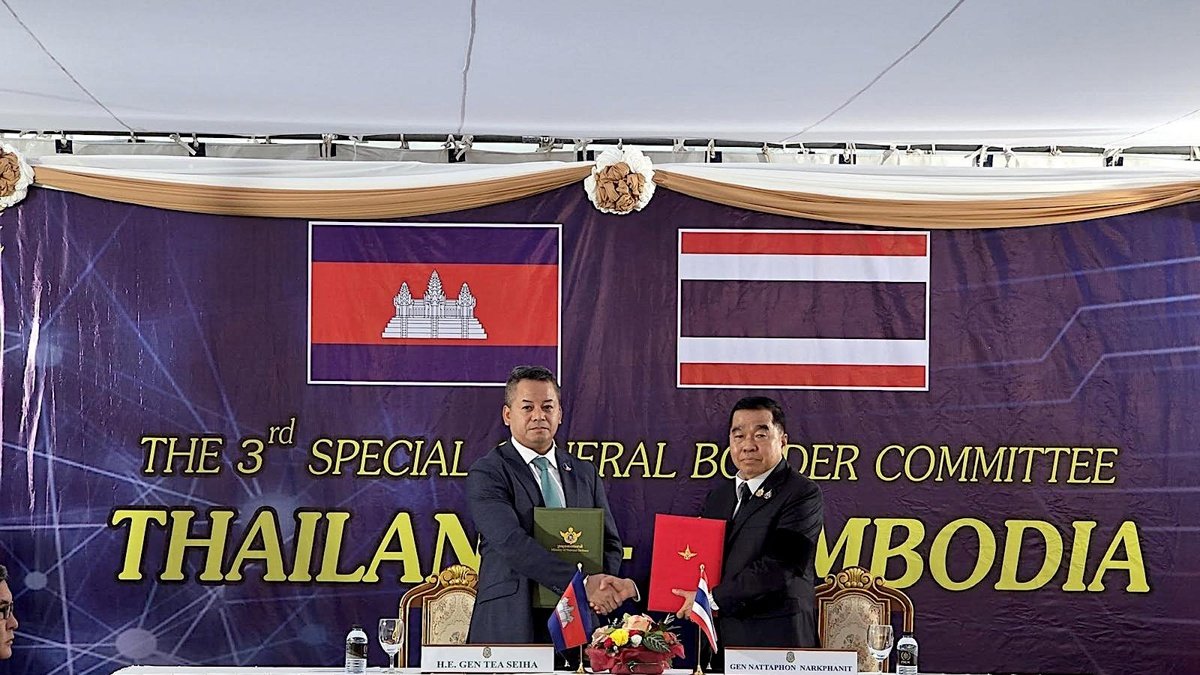 Tea Seiha (i) y Natthaphon Narkphanit (i), los ministros de Defensa de Camboya y Tailandia, respectivamente, intercambian el acuerdo firmado de cese al fuego.