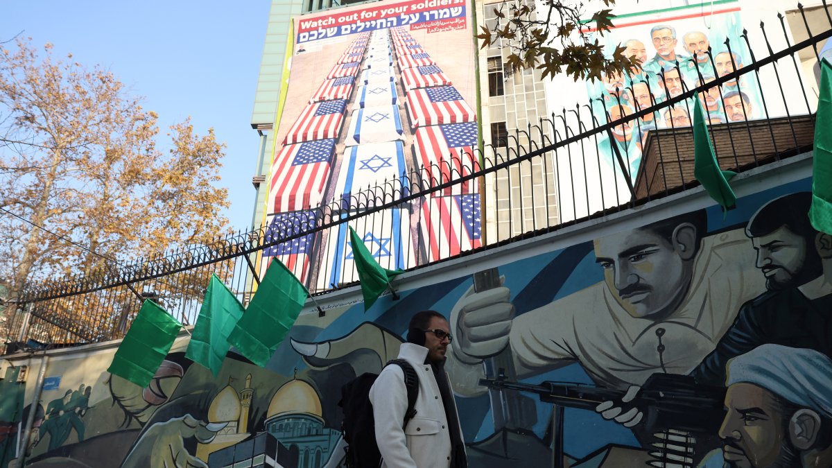 Un hombre iraní camina junto a una valla un mensaje del secretario del Consejo Supremo de Seguridad Nacional, Ali Larijani, que dice 