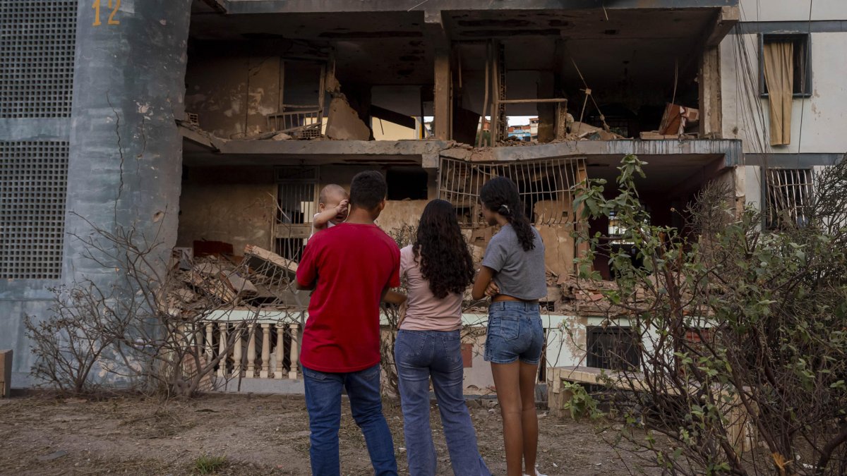 Personas observan un edificio afectado por un explosivo, este 4 de enero de 2026 en Catia La Mar (Venezuela).