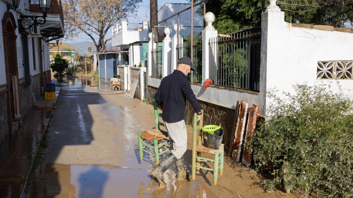Un vecino en el sur de España, limpia de lodo y barro el interior de su vivienda ante la crecida del río Guadalhorce y las precipitaciones intensas tras decretarse la alerta roja.