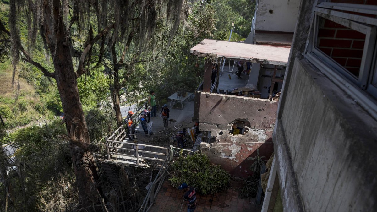 Trabajadores gubernamentales limpian escombros de una casa afectada tras ataque de EE.UU., el  6 de enero de 2026, en Caracas (Venezuela).