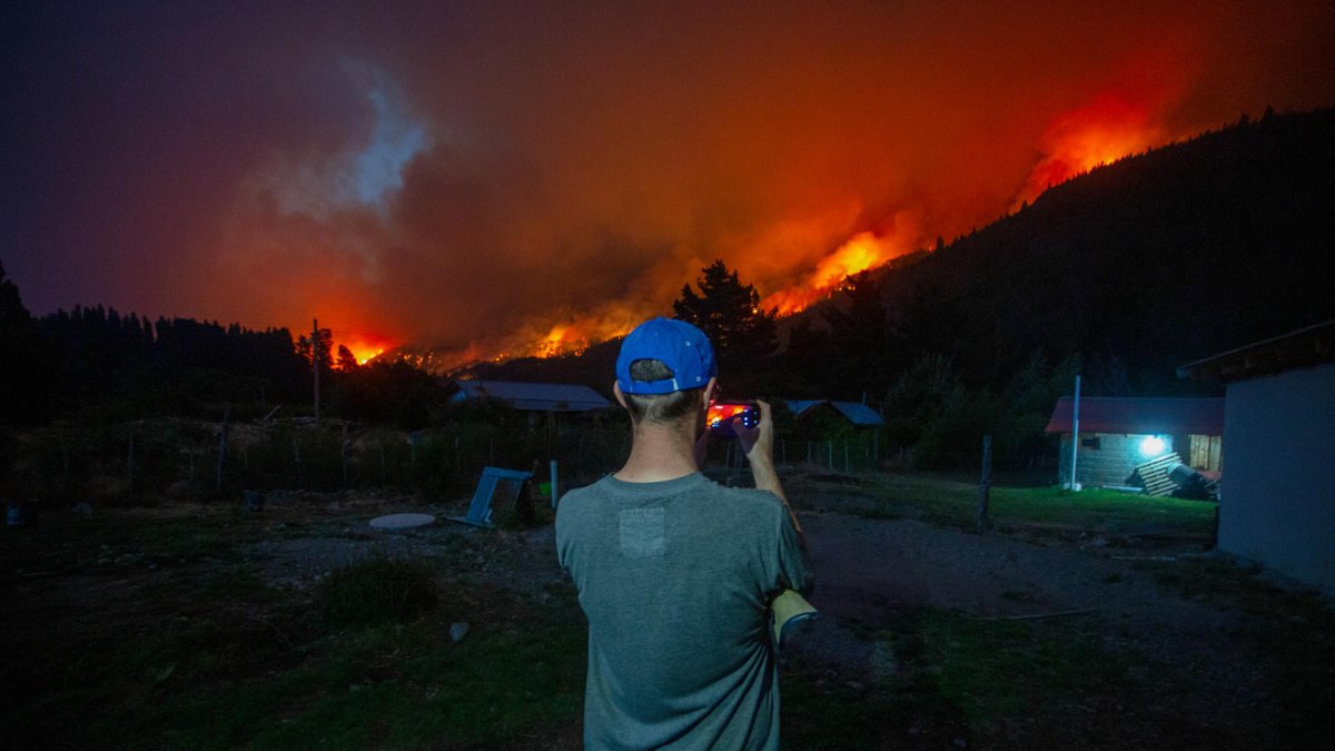 Un hombre toma una fotografía de los incendios forestales este miércoles, en el Hoyo provincia de Chubut (Argentina).