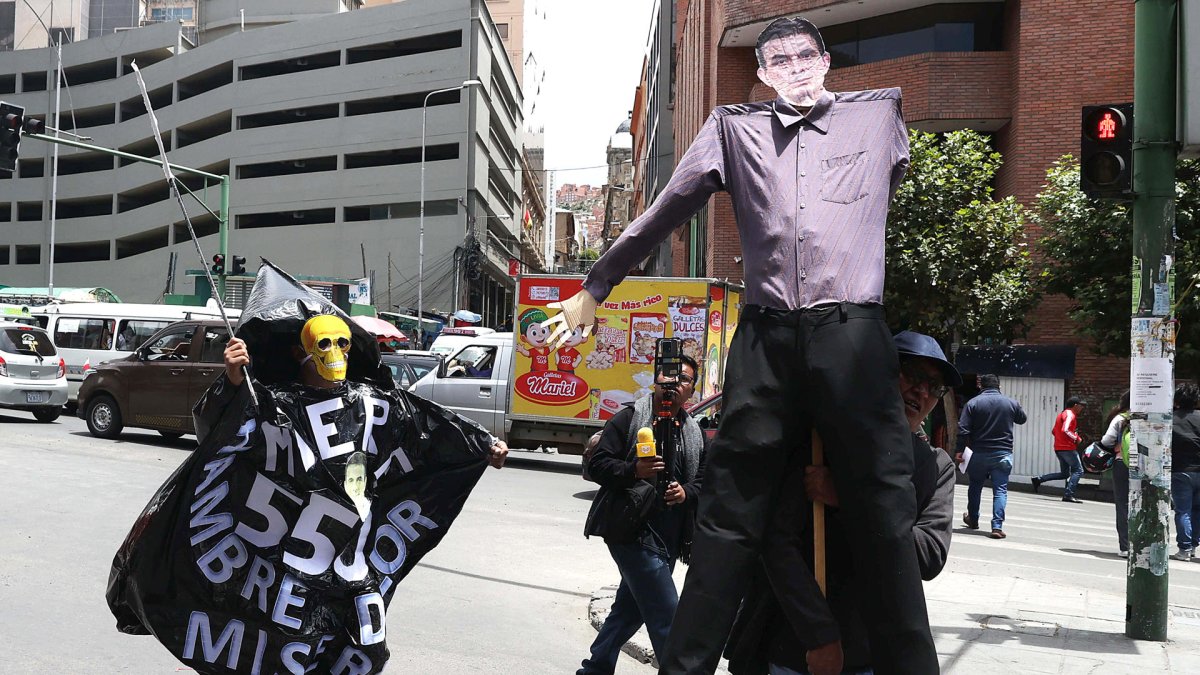 Una persona sostiene un muñeco con la imagen del presidente de Bolivia, Rodrigo Paz, durante una marcha este jueves en La Paz (Bolivia).