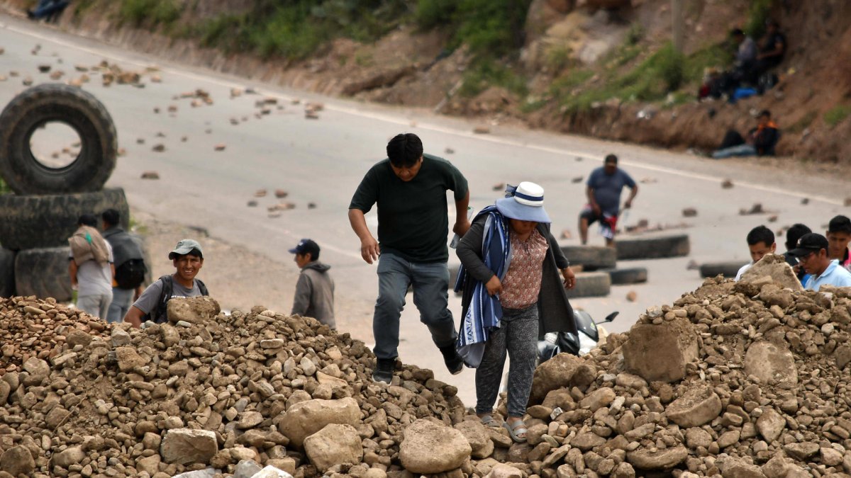 Personas caminan en medio de una carretera bloqueada este viernes, en Cochabamba (Bolivia).