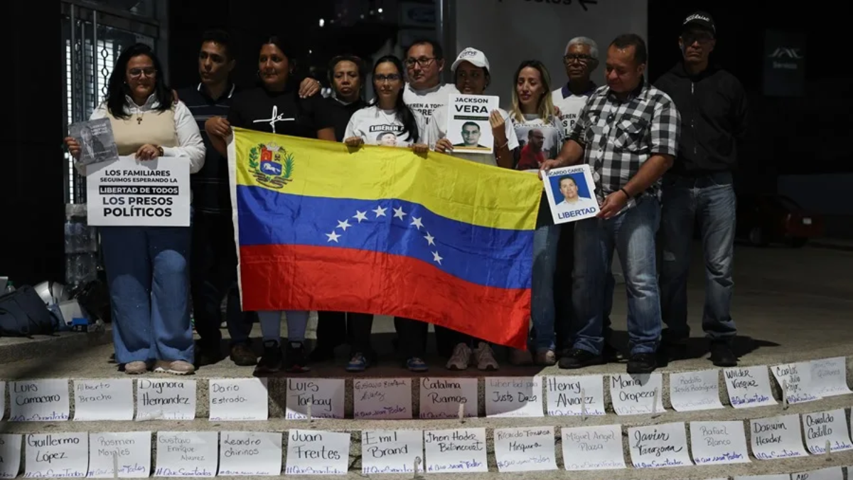 Familiares de presos políticos en Venezuela sostienen carteles en una vigilia, afuera de El Helicoide en Caracas.