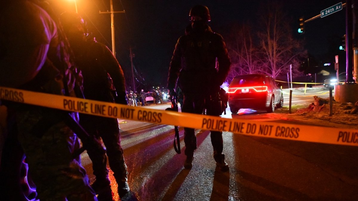 Agentes federales y policías detrás de cinta policial mientras estallan protestas tras el tiroteo de un hombre venezolano por parte de un agente de ICE en Mineápolis, el 14 de enero de 2026.