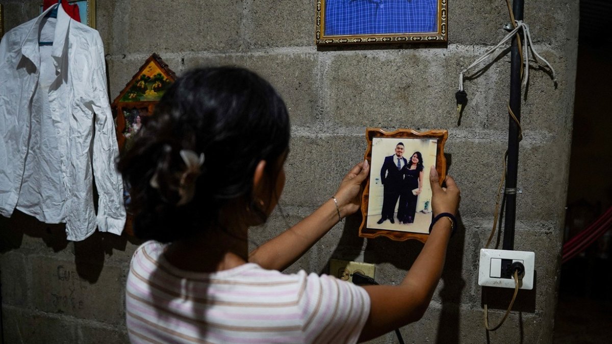 Jade, de 16 años, sostiene una fotografía de su padre, José Roger Urquilla, en su casa en El Rosario, El Salvador, el 3 de diciembre de 2025.