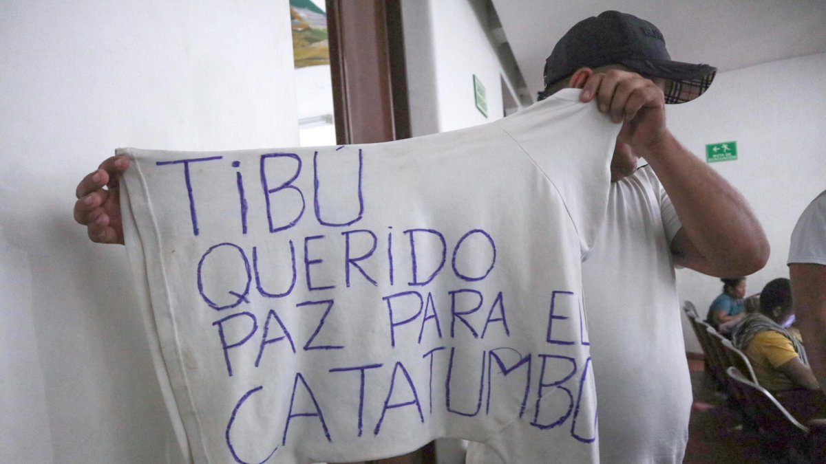 Un hombre desplazado por la violencia mostrando una camiseta con una nota escrita pidiendo paz para el Catatumbo en Cúcuta (Colombia).