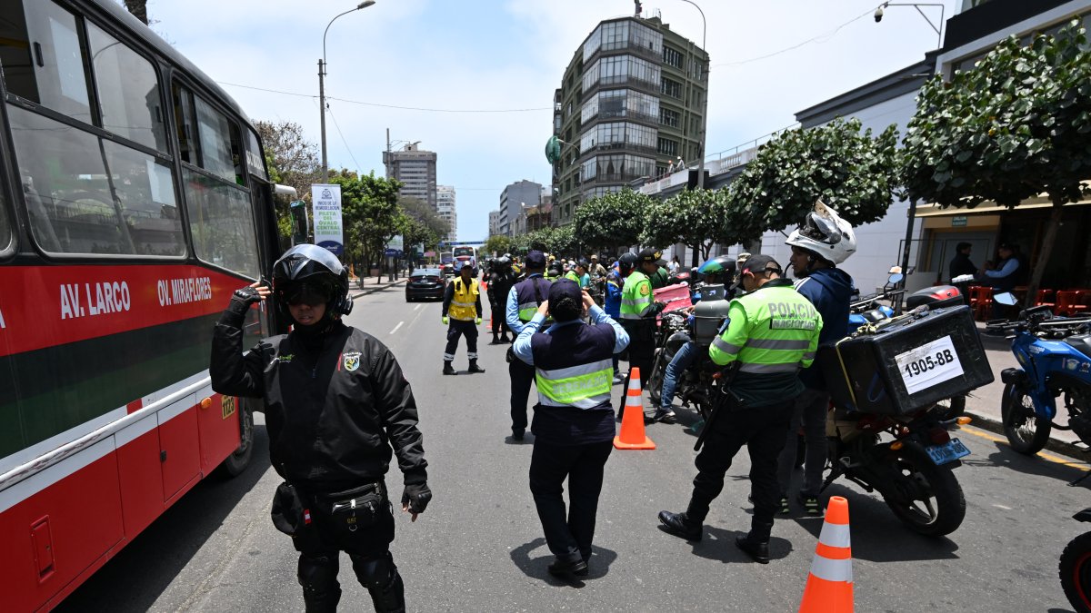 Agentes policiales registran a motociclistas en un puesto de control después de que el gobierno declarara el estado de emergencia en Lima.