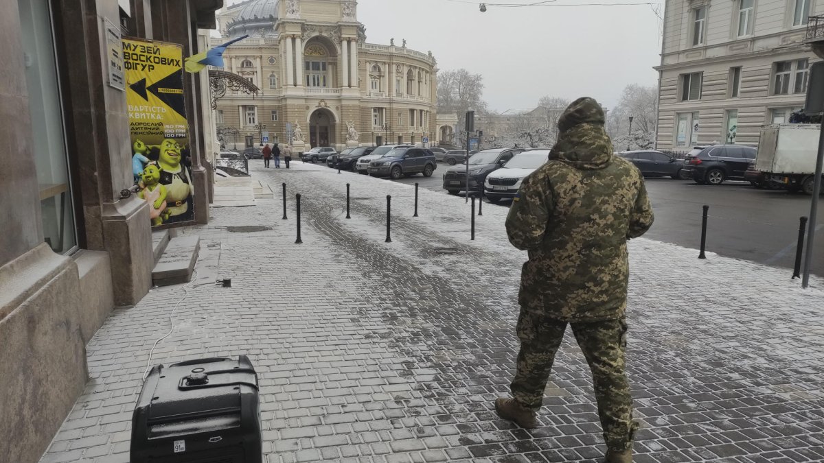 Un soldado ucraniano pasa por delante de un generador de diésel con la ópera de Odesa de fondo.