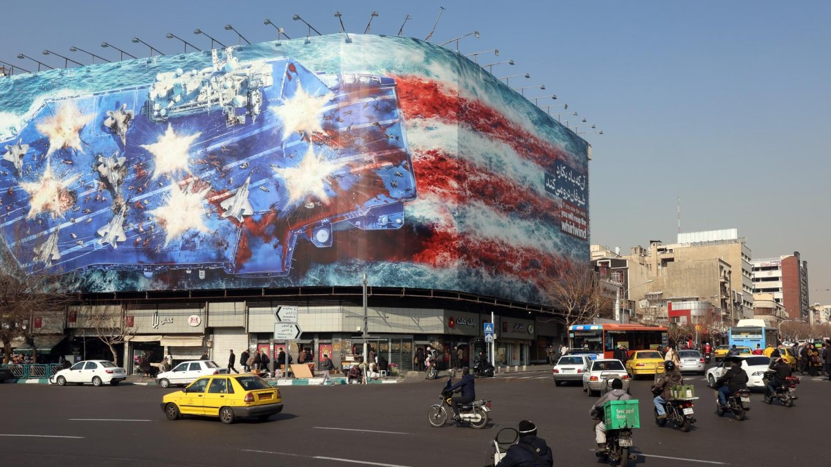 Los vehículos circulan cerca de una enorme valla publicitaria antiestadounidense colgada en la plaza Enqelab en Teherán, Irán, el 27 de enero de 2026.