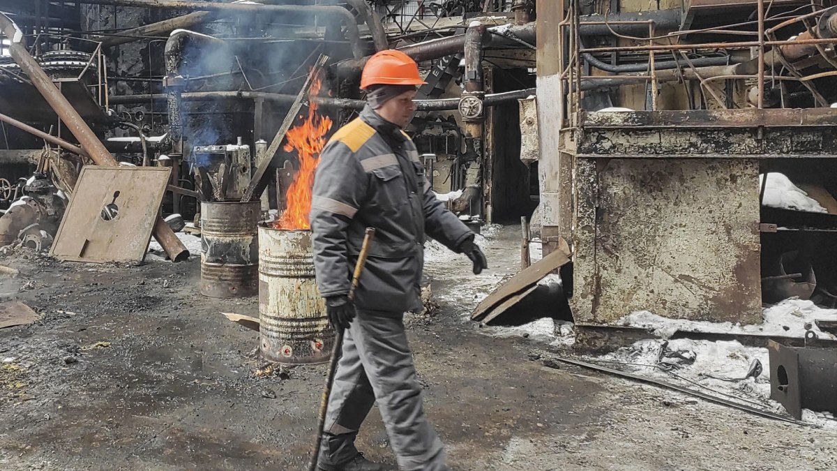 Andriy, un electricista, cerca de los barriles con leña encendida, instalados para calentar la sección dañada de una planta de energía térmica en Ucrania después de los ataques rusos.