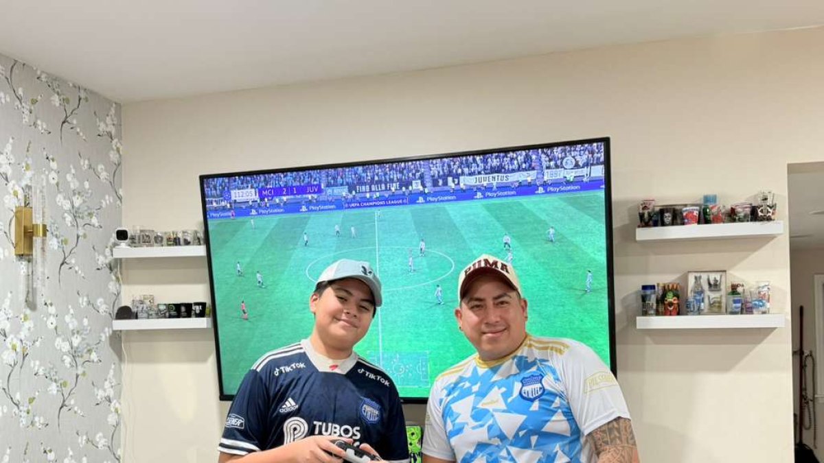 Ahidam (i) y su padre comparten la afición por Emelec y el fútbol hasta en los videojuegos.