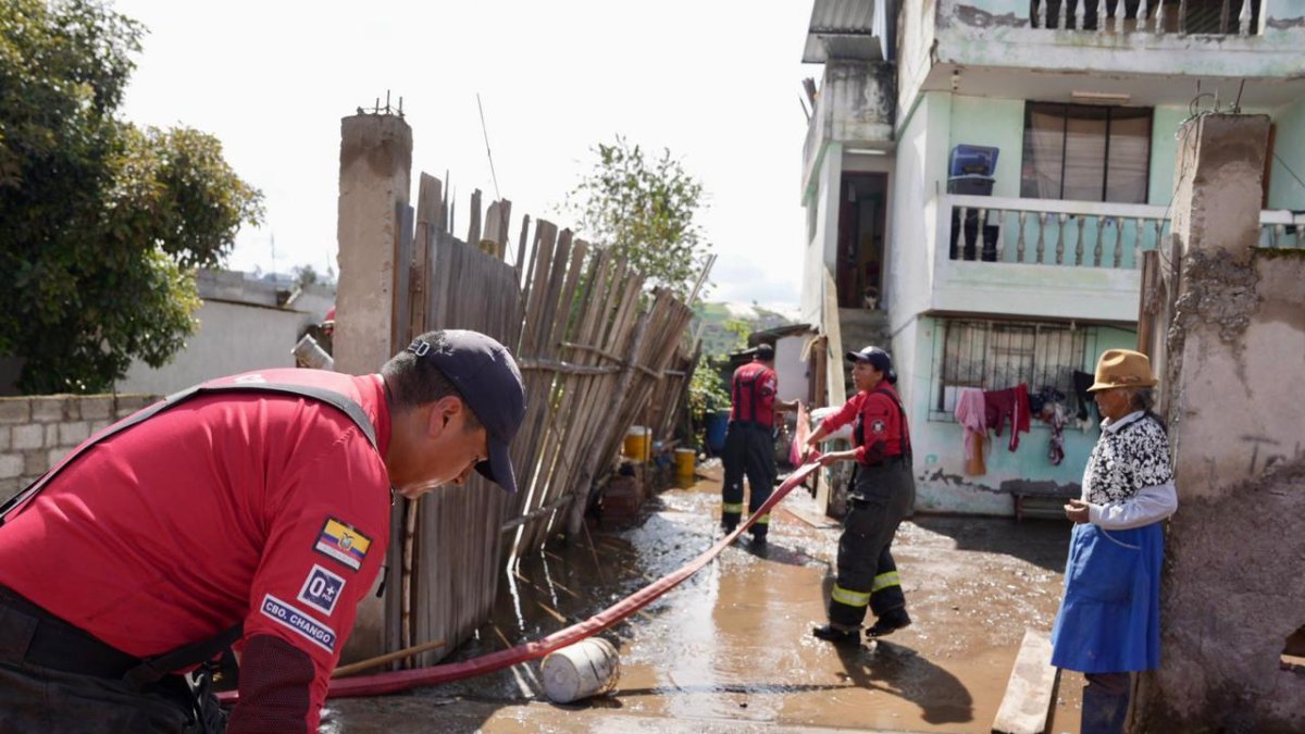 La adulta mayor afectada observa a los miembros del Cuerpo de Bomberos realizar su trabajo.