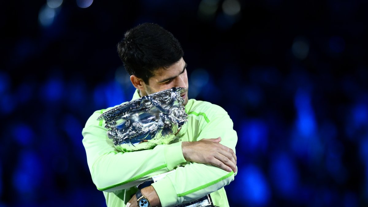 El español Carlos Alcaraz abraza el trofeo del Abierto de Australia que con 22 años y 272 días, es el más joven en lograrlo.