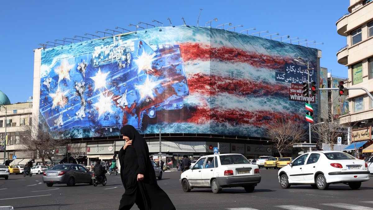 Una mujer iraní con velo camina cerca de un enorme cartel antiestadounidense colgado en la plaza Enqelab en Teherán, el sábado 31 de enero de 2026.
