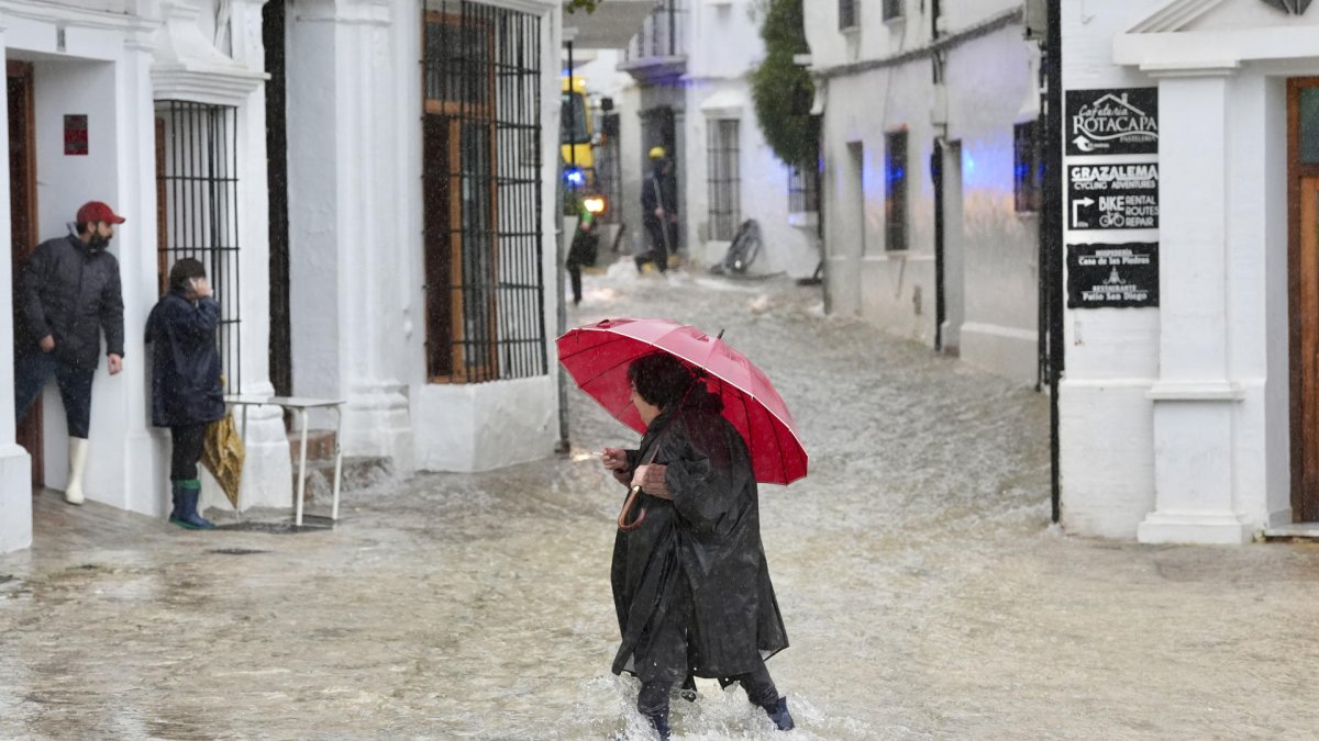 Una vecina de Grazalema (Cádiz) camina por una calle inundada debido a las intensas lluvias.
