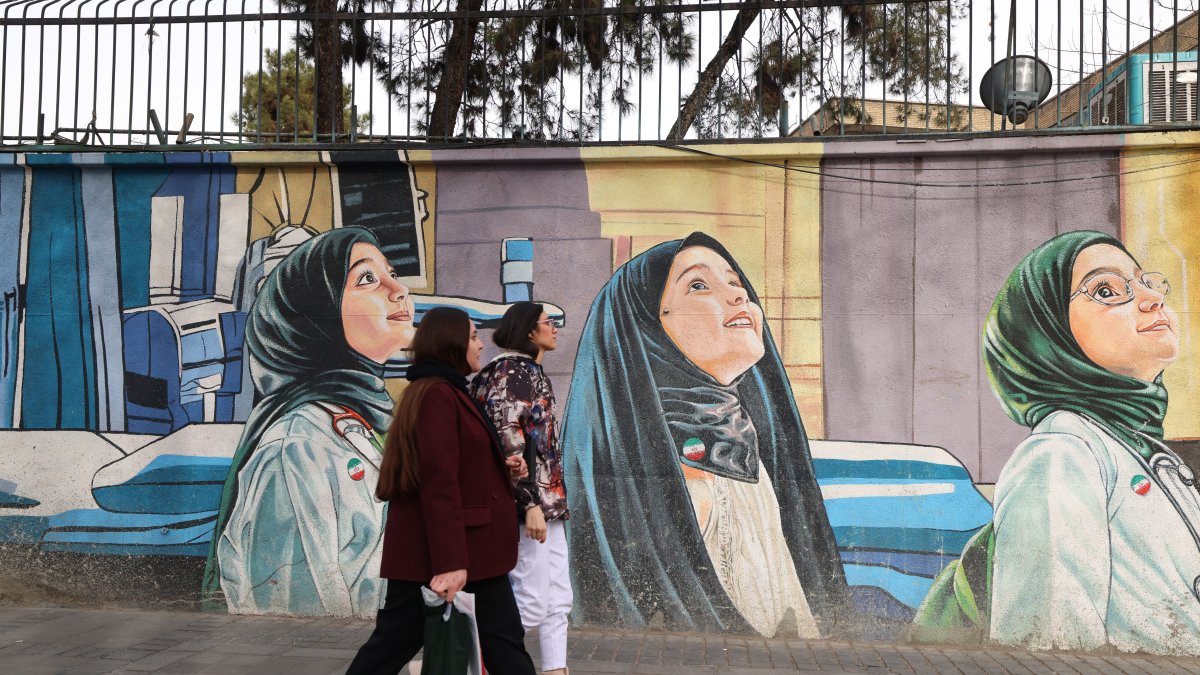 Mural. Mujeres pasan frente a un mural representativo, en Tehran.