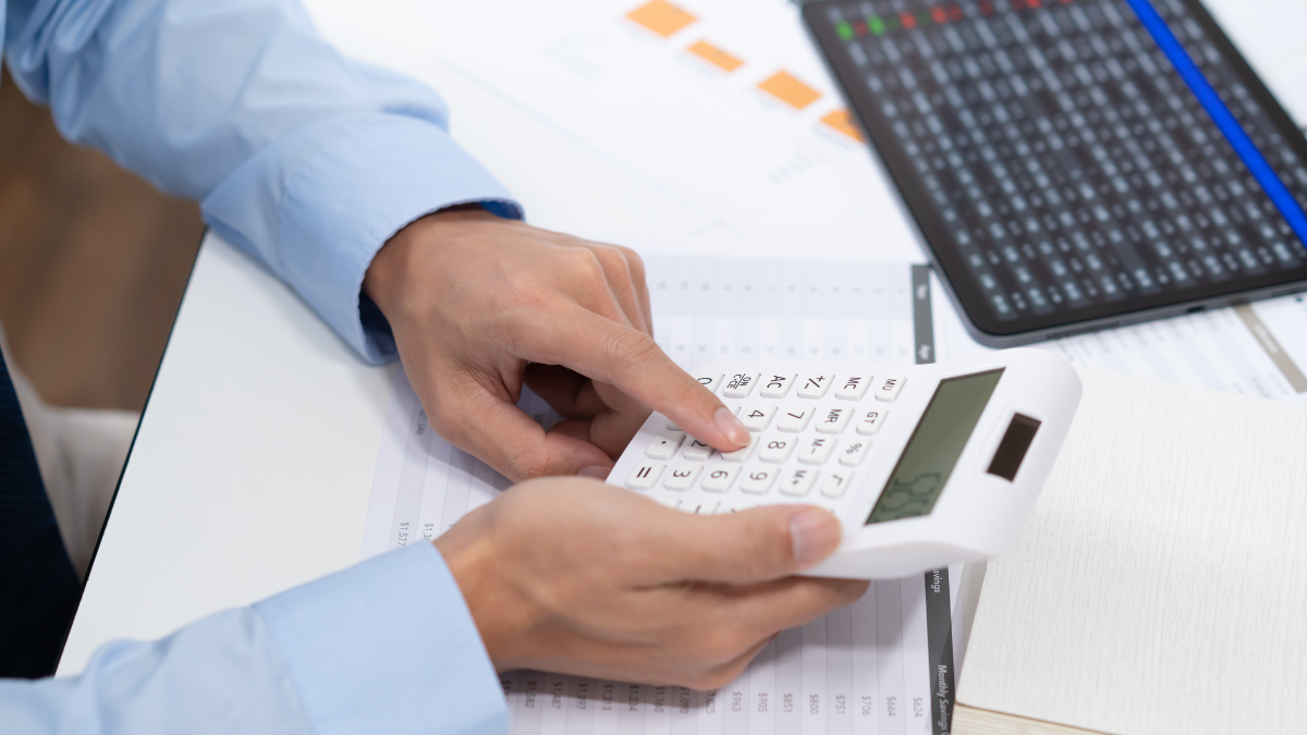 Referencial.Una persona revisa documentos financieros y utiliza una calculadora, en el marco de los requisitos para acceder al crédito Emprende Violeta de 500 dólares.