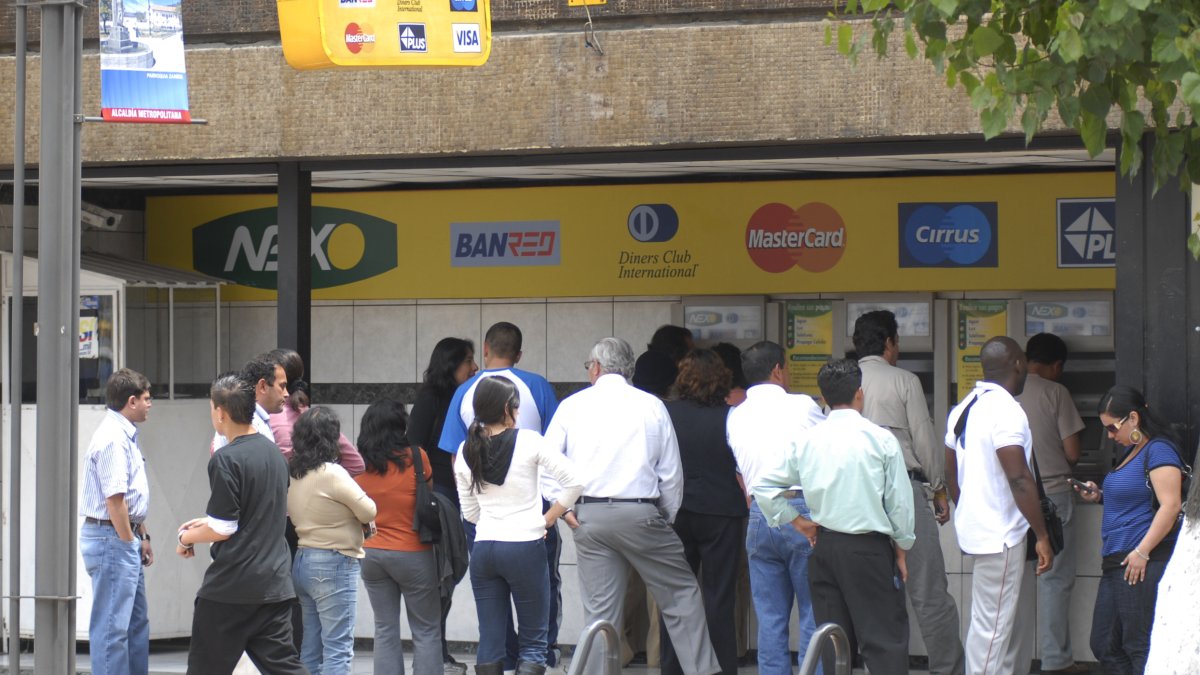 Un grupo de personas realizan fila en cajeros automáticos de una entidad bancaria en Quito.