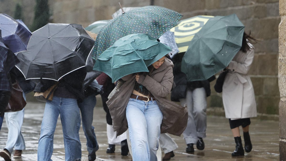 Varias personas se protegen de la lluvia en el noroeste de España.