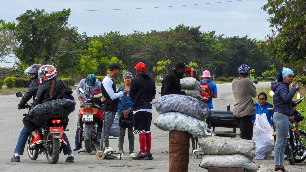 Venta. Personas compran carbón en una carretera de La Habana. Así, se esfuerzan por sobrellevar apagones constantes y escasez que empeoran bajo la presión económica de EE.UU.