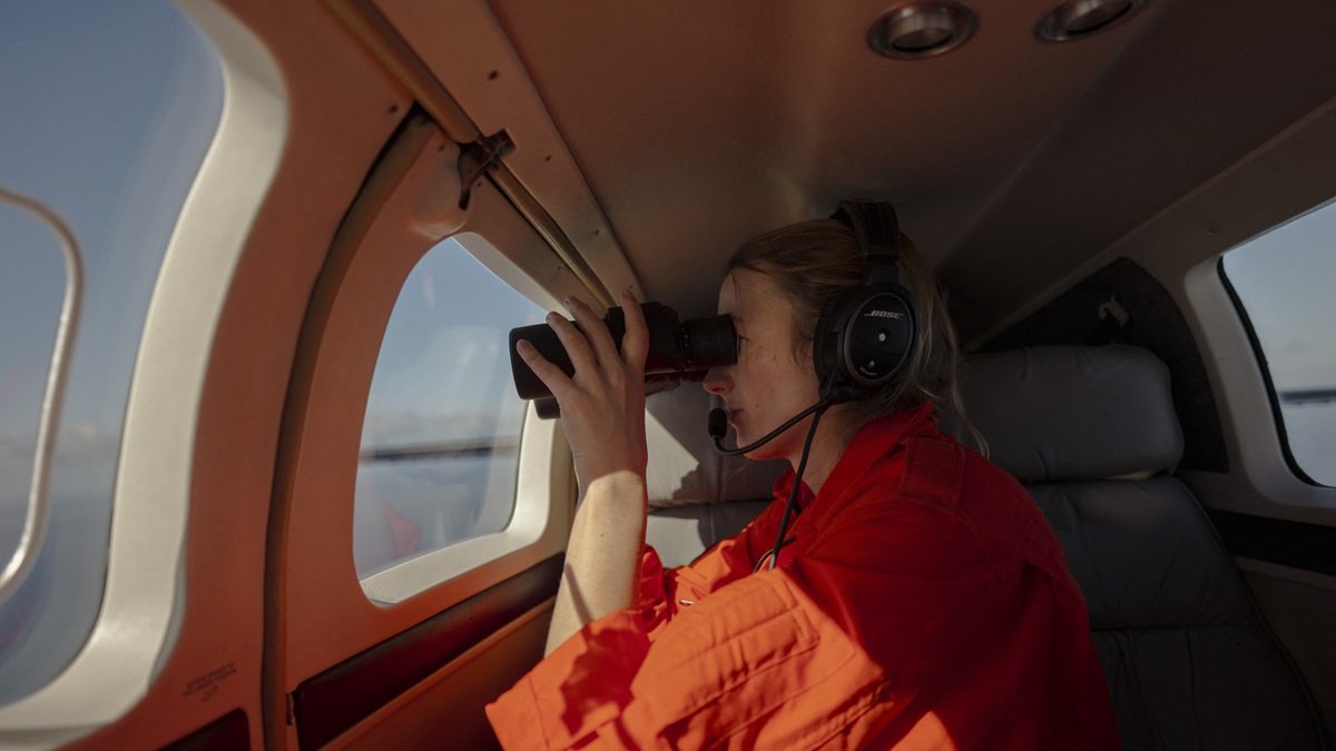 El Coordinador Táctico de la Iniciativa Piloto Humanitaria (HPI) escanea el océano con un par de binoculares durante una misión de patrullaje el 22 de enero de 2025.