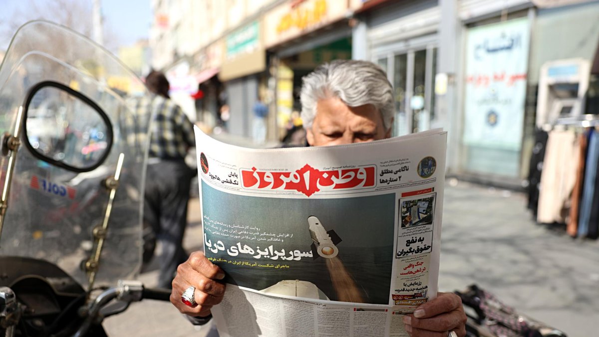 Mientras Estados Unidos continúa reforzando su presencia militar en Oriente Medio, un hombre lee el diario iraní con el titular