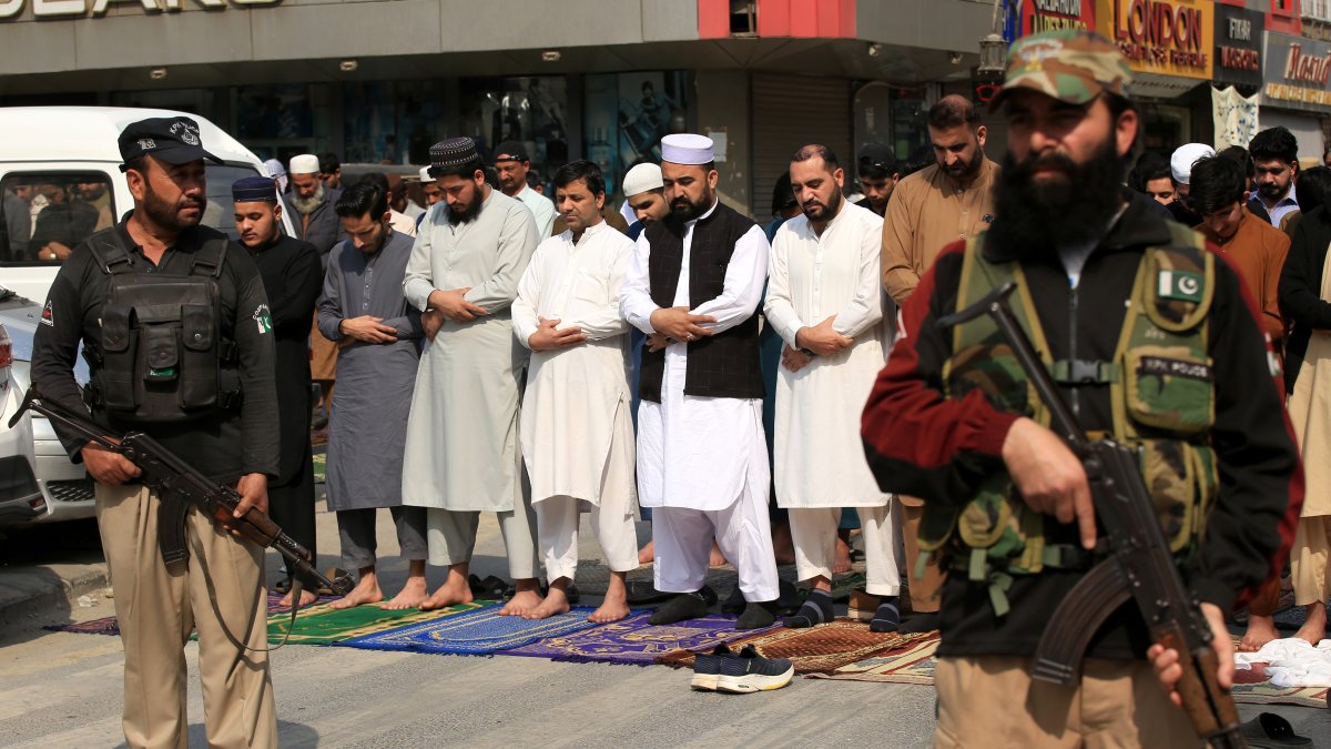 Oficiales de seguridad y musulmanes civiles en una calle de Peshawar, en Pakistán.