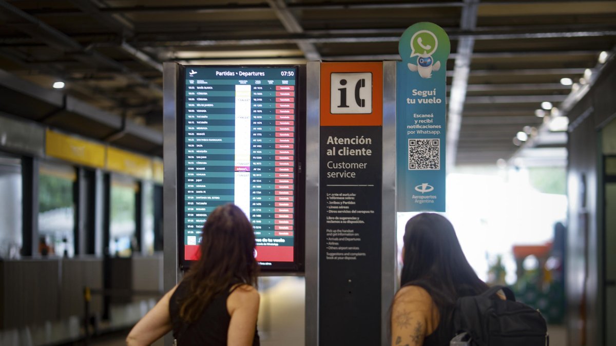 Dos pasajeras observan una pantalla informativa que muestra los vuelos cancelados en el Aeropuerto Internacional Jorge Newbery de Buenos Aires.