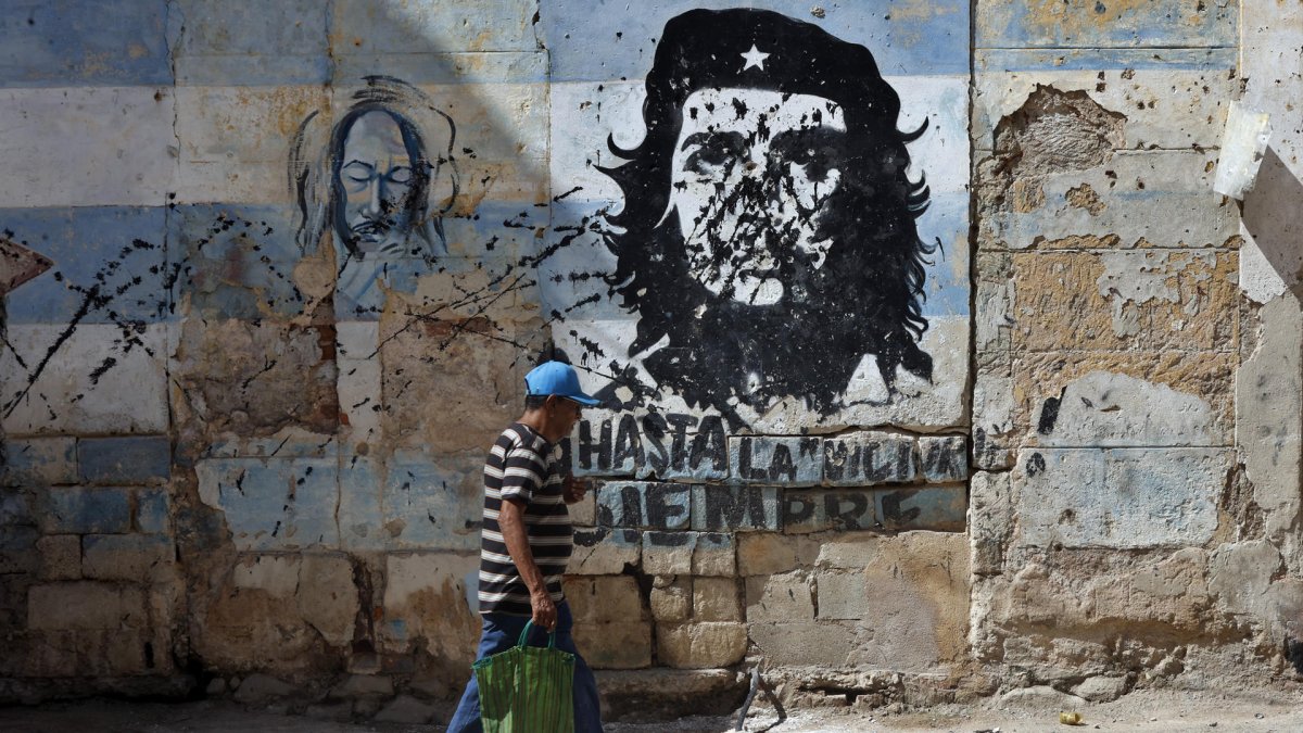 Una persona camina frente a un mural con la imagen de Ernesto 'Che' Guevara este jueves, en una calle de La Habana (Cuba).