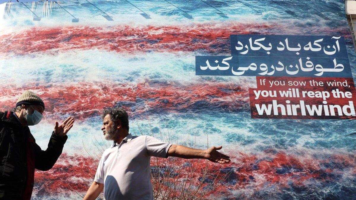 Iraníes conversan frente a un cartel antiestadounidense en Teherán, Irán, el 25 de febrero de 2026.