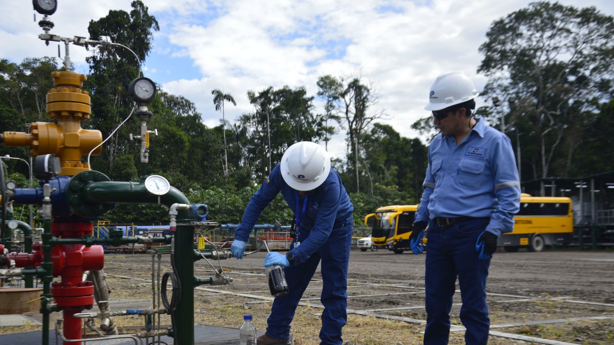 Personal de Petroecuador trabaja cerca de una torre de extracción de petróleo.