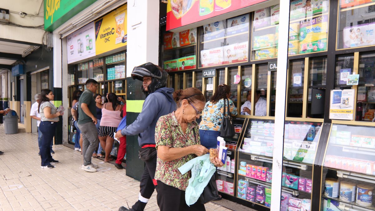 Una mujer revisa la factura de la medicina que ha comprado sorprendida de que ahora cuesta más.